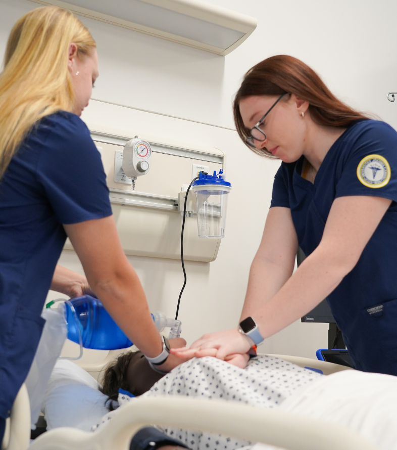 two female jcu students practicing cpr on a medical manniquin