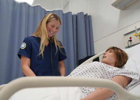 nursing student smiling at medical mannikin