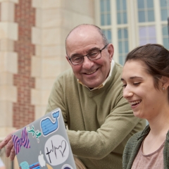 Faculty member helping student looking at her laptop outside on the stairs of the Administration Building